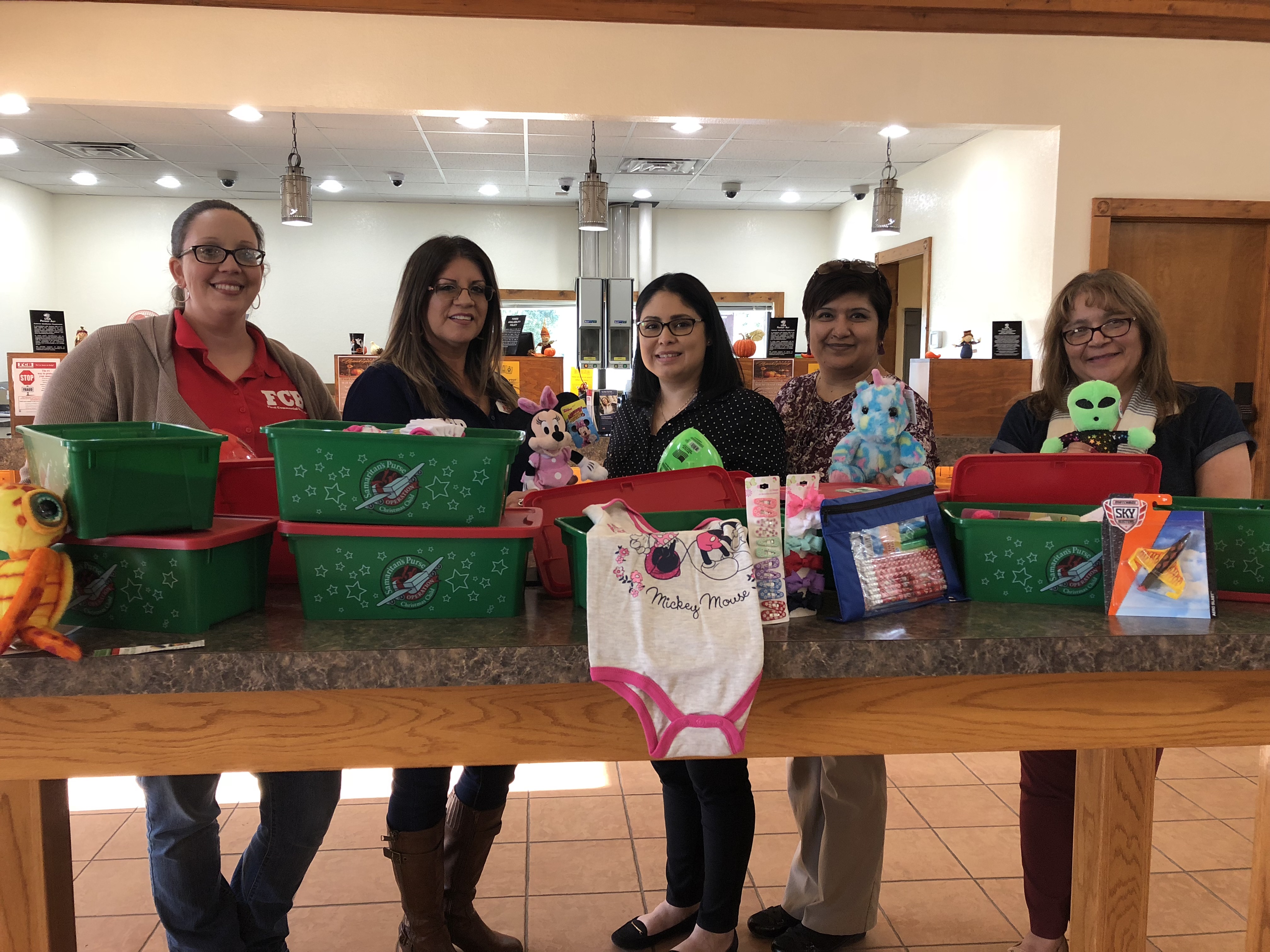 five people standing behind a table of presents