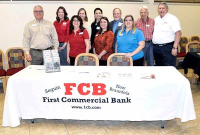 nine members of the First Commercial Bank staff standing behind a table